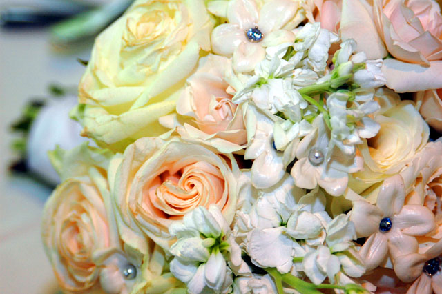 A wedding bouquet consisting of roses, sweet peas and stephanotis flowers, as well as pearl and crystal accents. Its French-braided ribbon handle added the perfect touch of elegance.