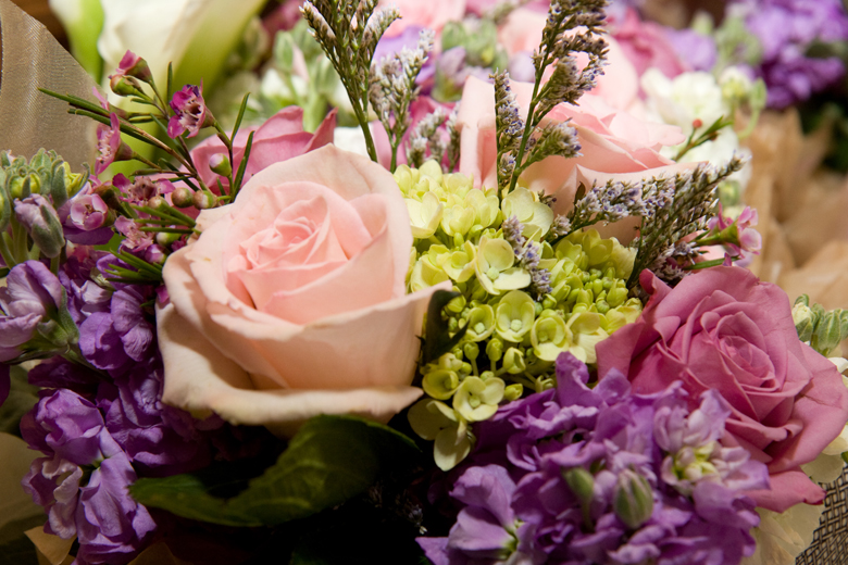 A bridesmaid's bouquet of pink and mauve roses with purple and light green filler flowers.