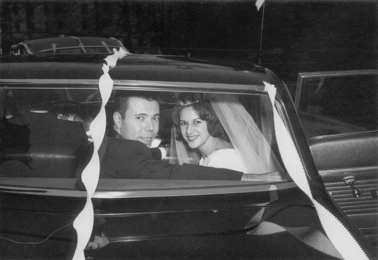1960s bride and groom in their decorated just married car
