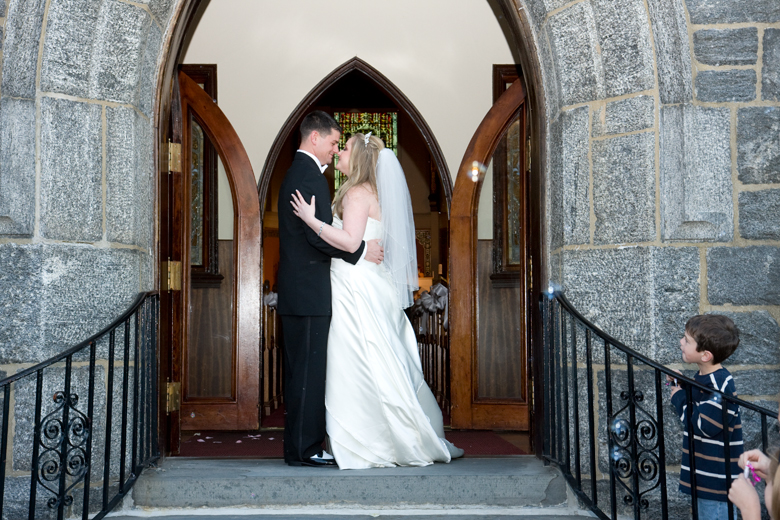 couple nuzzle in church doorway