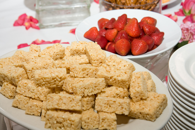 A plate of rice krispy treats and a bowl of fresh strawberries, a perfect combination.