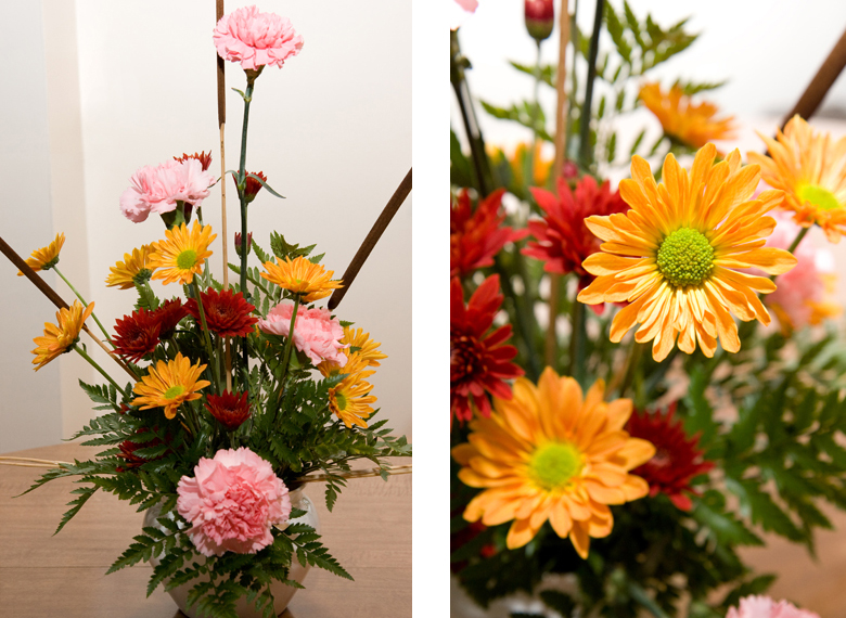 A centerpiece consisting of orange and maroon chrysanthemums and pink carnations.